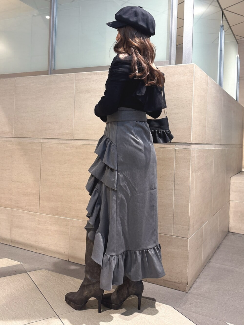 ブラック系のハンドバッグ、ブラック系のニット/セーター、グレー系のスカートを着用したレディースの春コーディネートの2枚目の写真