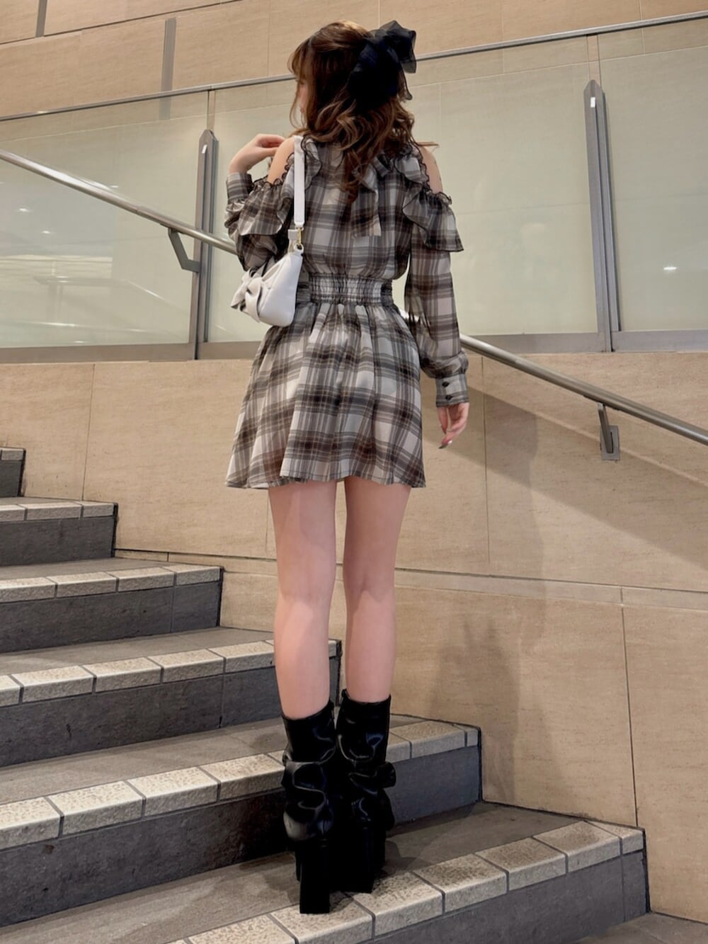 ブラウン系のワンピース、ブラック系のブーツ、ホワイト系のハンドバッグを着用したレディースの春コーディネートの6枚目の写真