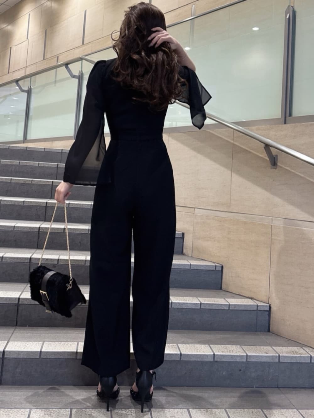 ブラック系のワンピース、ブラック系のハンドバッグ、ブラック系のパンプスを着用したレディースの冬コーディネートの5枚目の写真