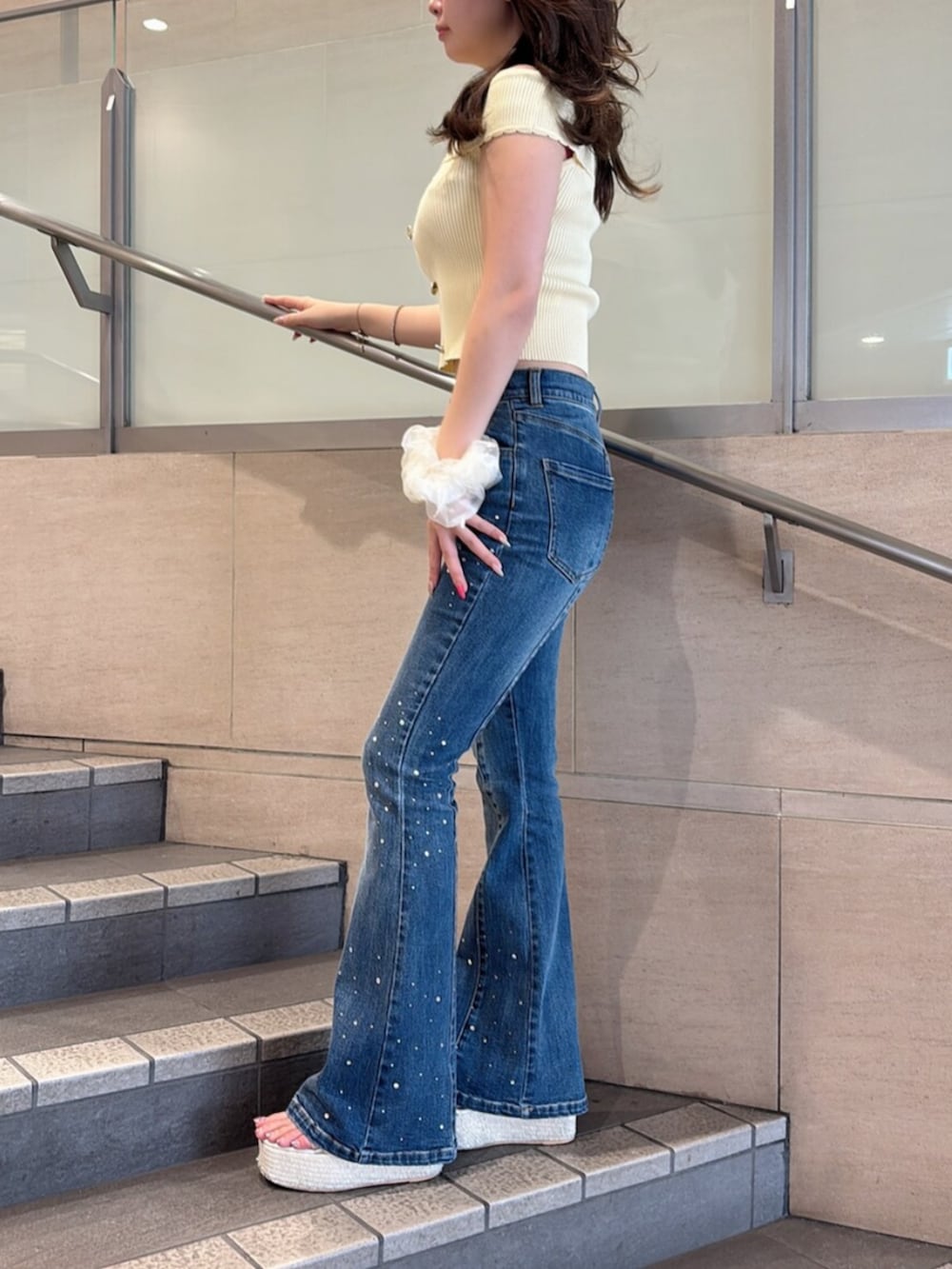 ホワイト系のサンダル、イエロー系のニット/セーター、ブルー系のデニムパンツを着用したレディースの夏コーディネートの2枚目の写真