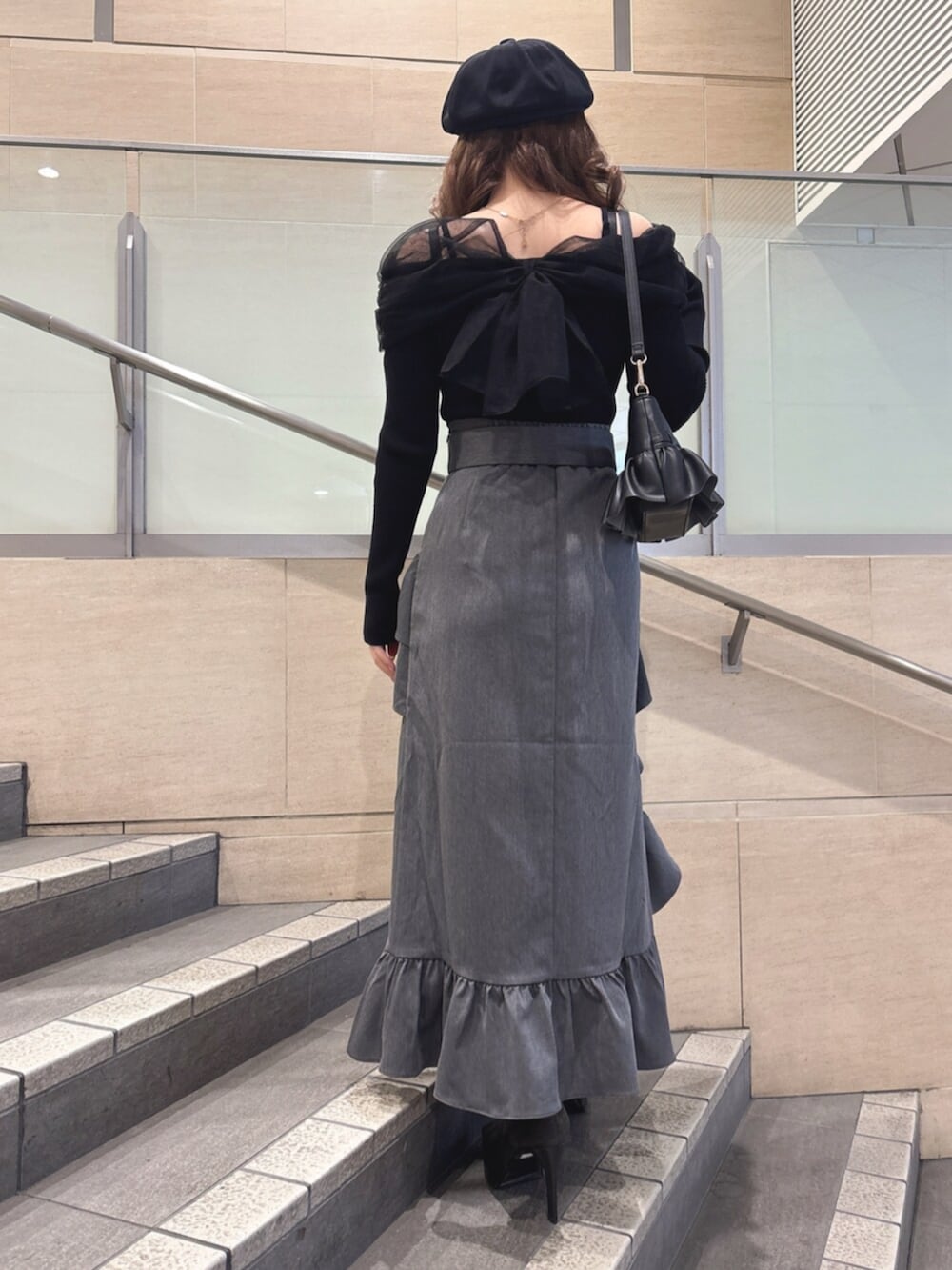 ブラック系のハンドバッグ、ブラック系のニット/セーター、グレー系のスカートを着用したレディースの春コーディネートの3枚目の写真