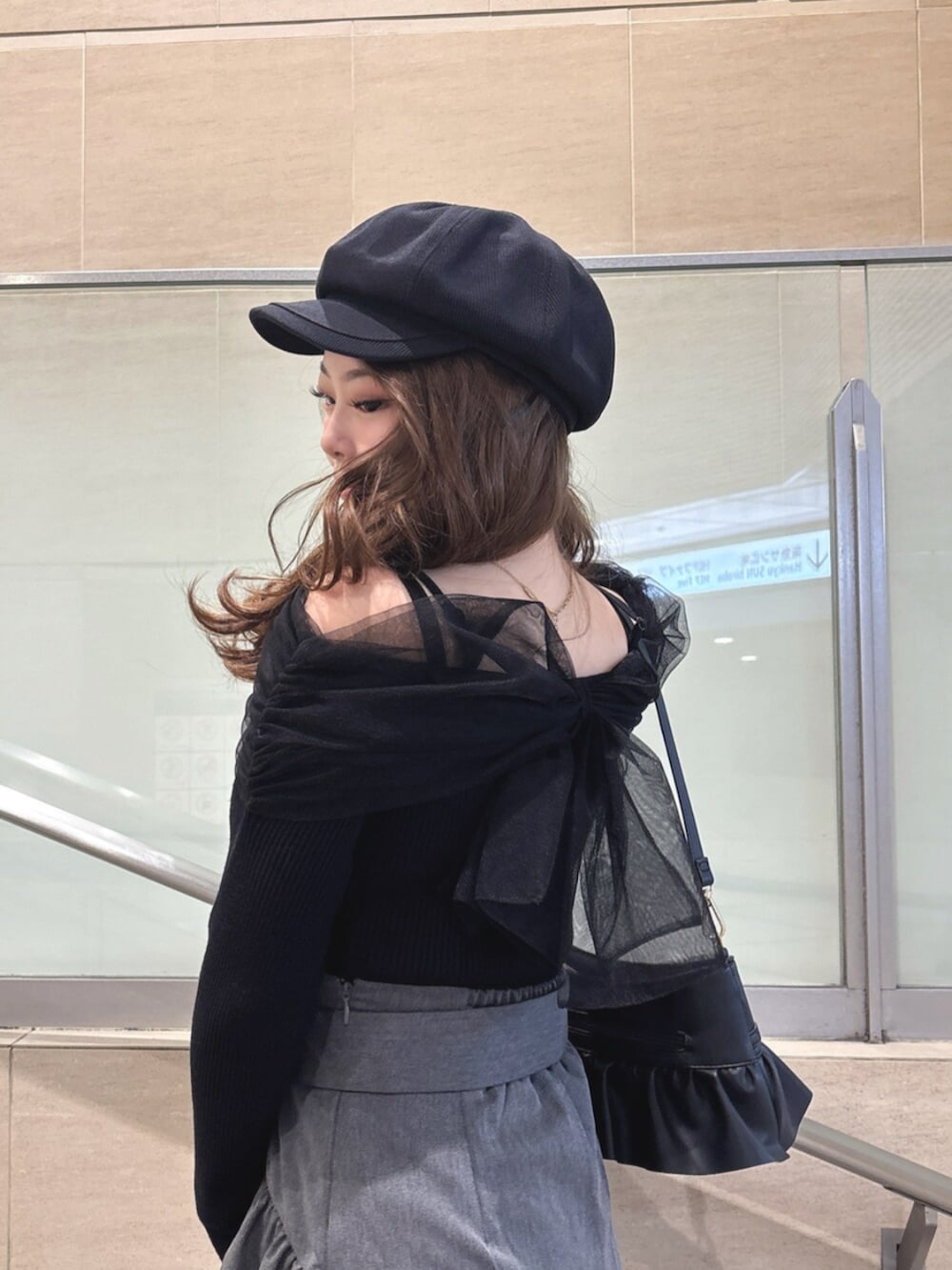 ブラック系のハンドバッグ、ブラック系のニット/セーター、グレー系のスカートを着用したレディースの春コーディネートの6枚目の写真