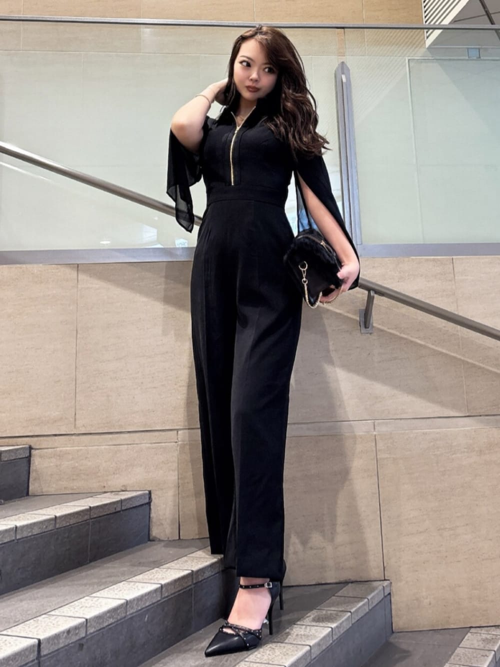 ブラック系のワンピース、ブラック系のハンドバッグ、ブラック系のパンプスを着用したレディースの冬コーディネートの3枚目の写真