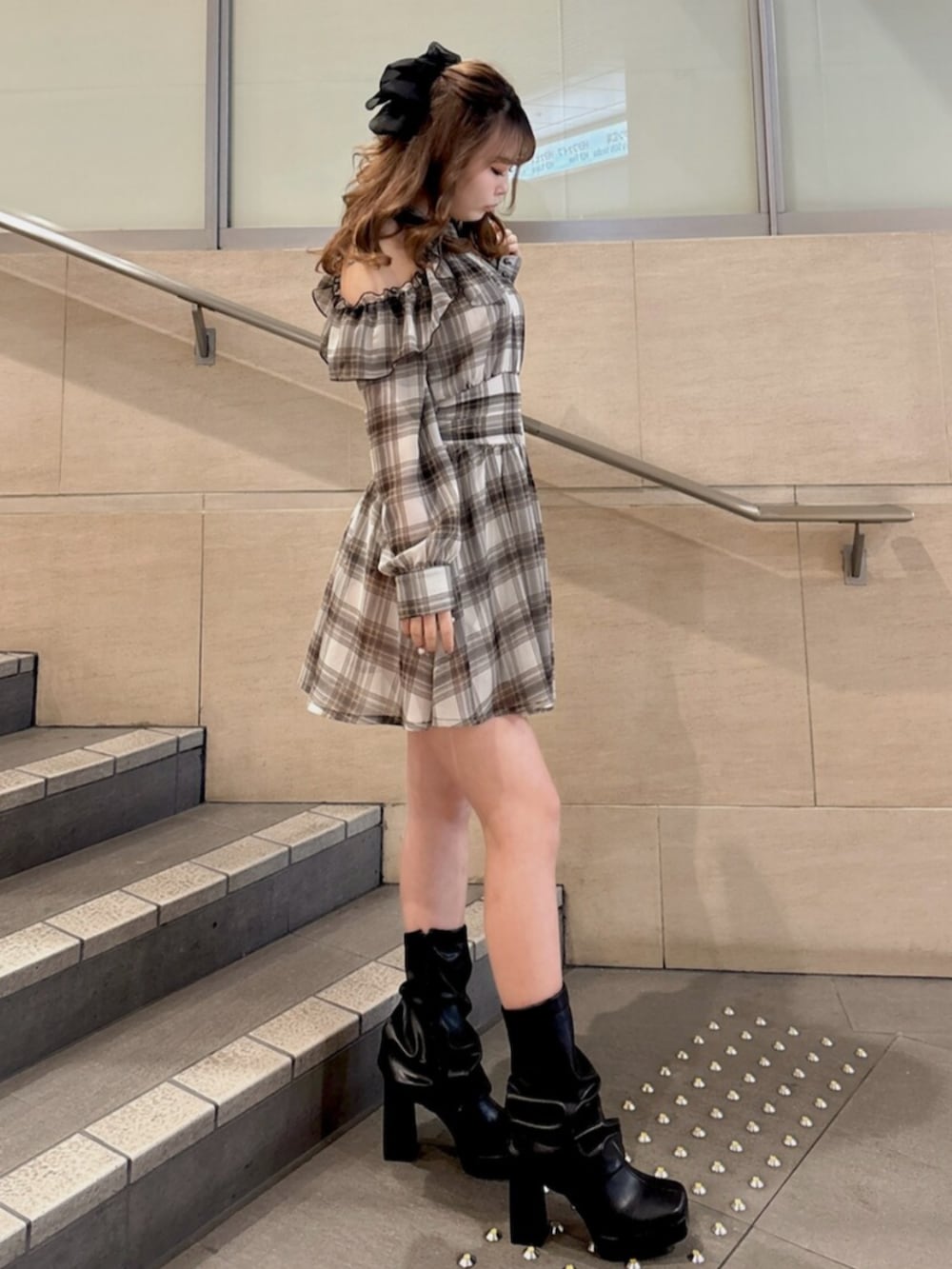 ブラウン系のワンピース、ブラック系のブーツ、ホワイト系のハンドバッグを着用したレディースの春コーディネートの2枚目の写真