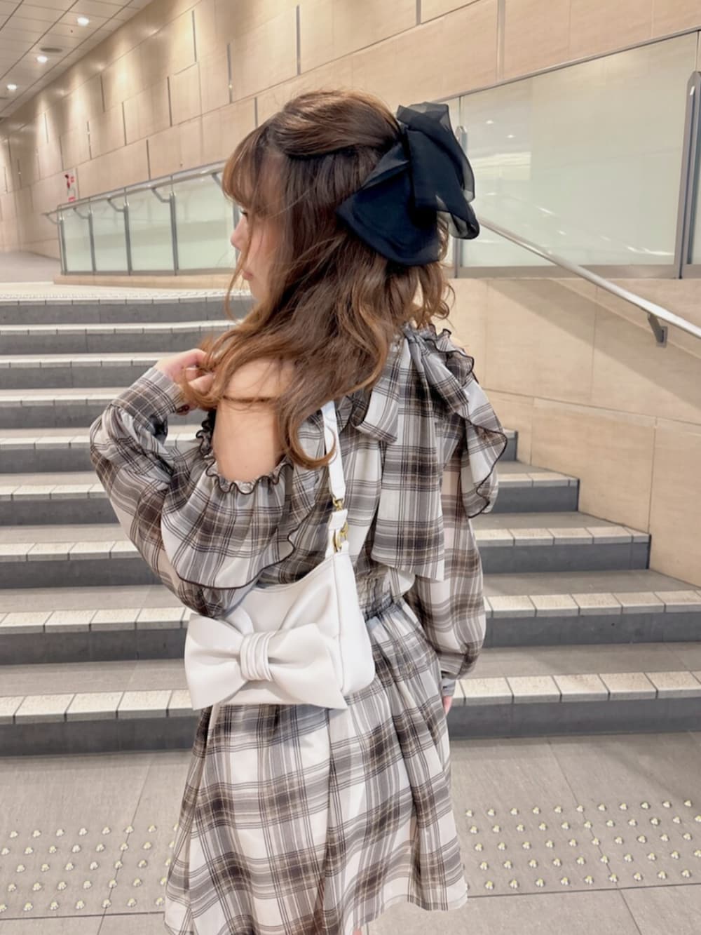 ブラウン系のワンピース、ブラック系のブーツ、ホワイト系のハンドバッグを着用したレディースの春コーディネートの5枚目の写真