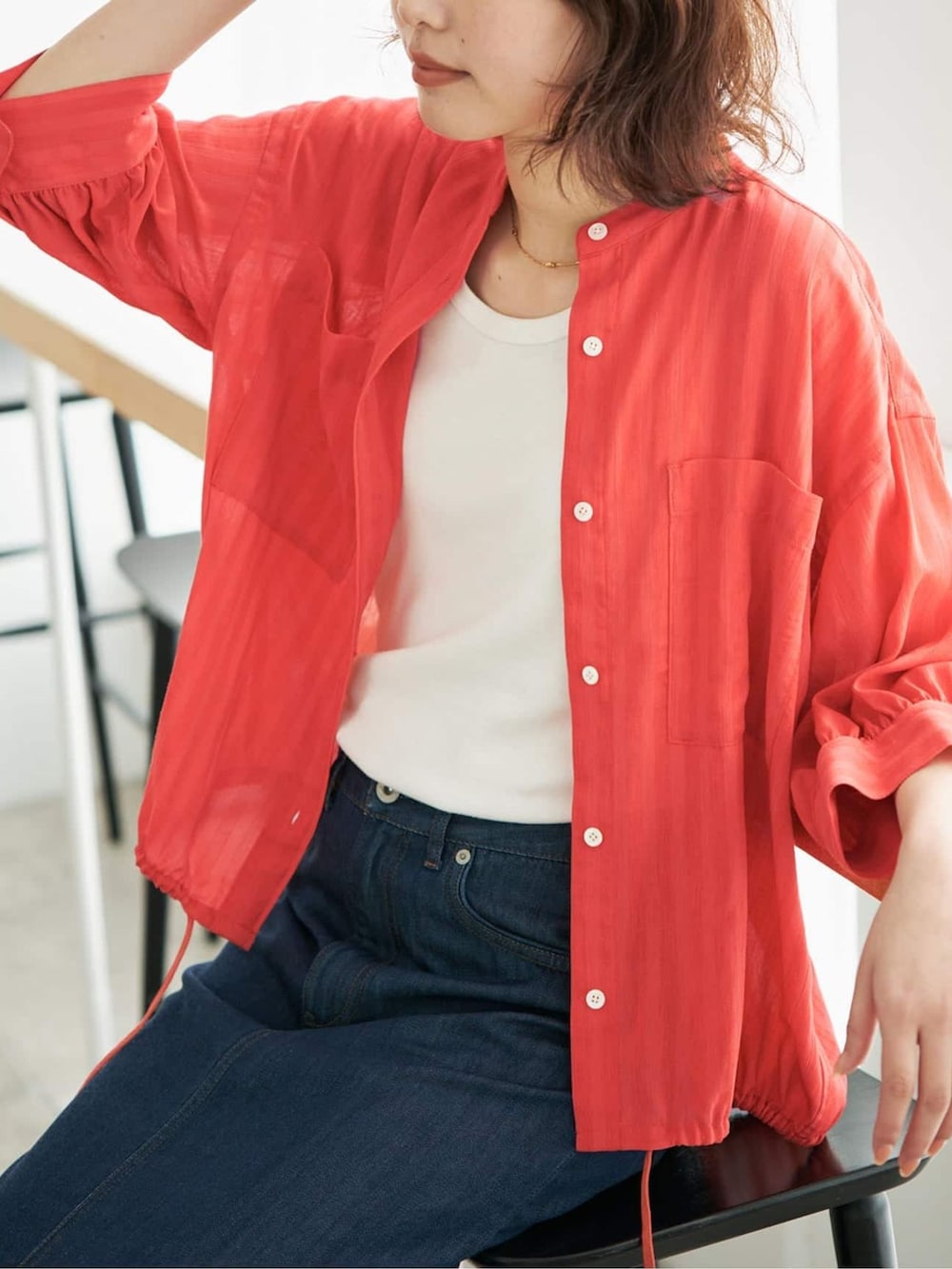 レッド系のシャツ/ブラウス、ブルー系のデニムスカート、ブラック系のクラッチバッグを着用したレディースの春コーディネートの4枚目の写真