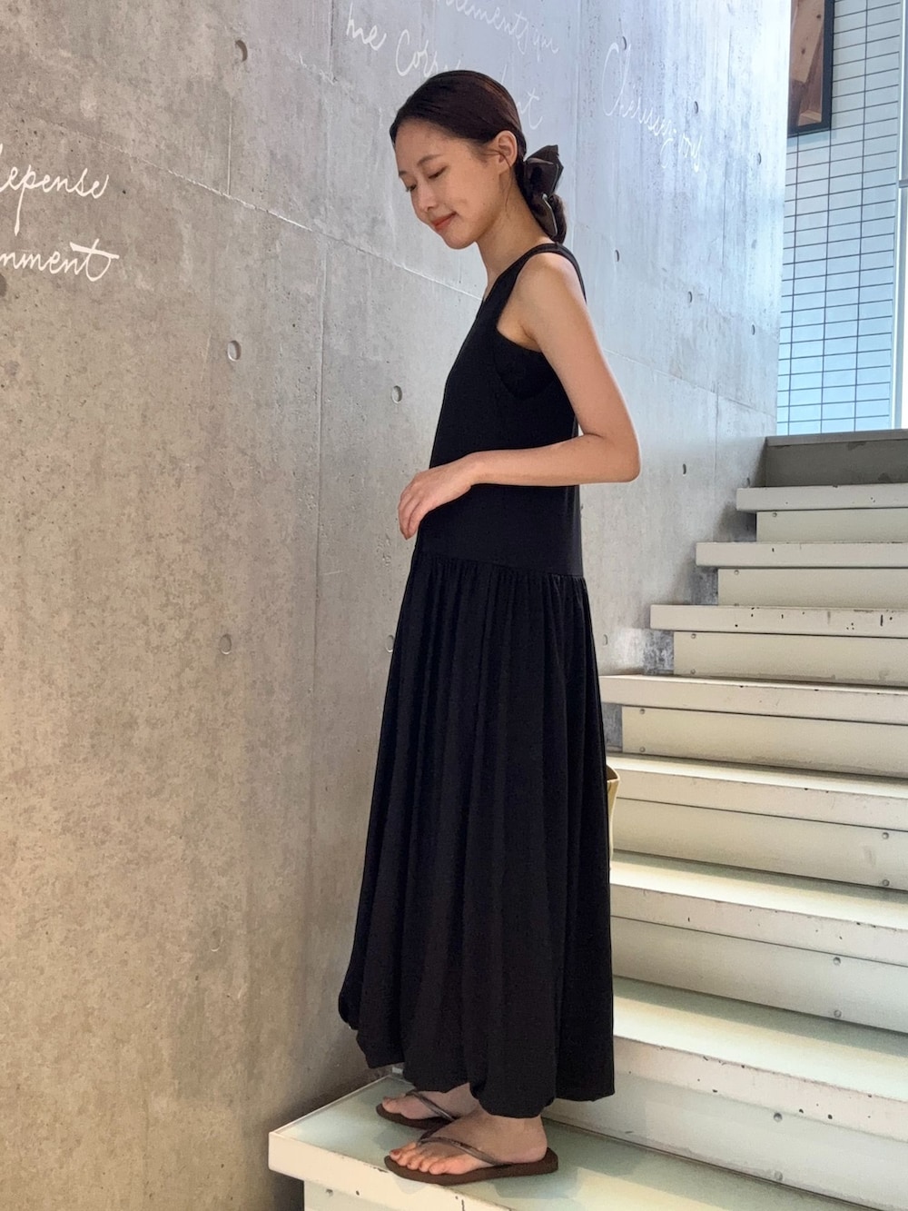 ブラック系のワンピース、ブラウン系のサンダルを着用したレディースの夏コーディネートの2枚目の写真
