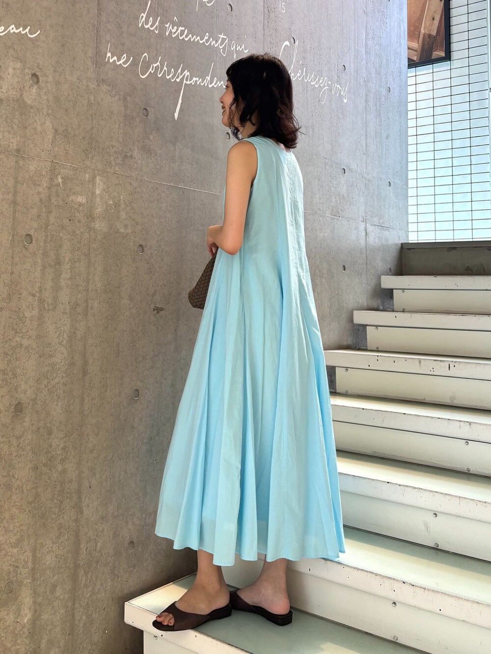 ブルー系のワンピース、ブラウン系のトートバッグ、ブラウン系のサンダルを着用したレディースの夏コーディネートの2枚目の写真