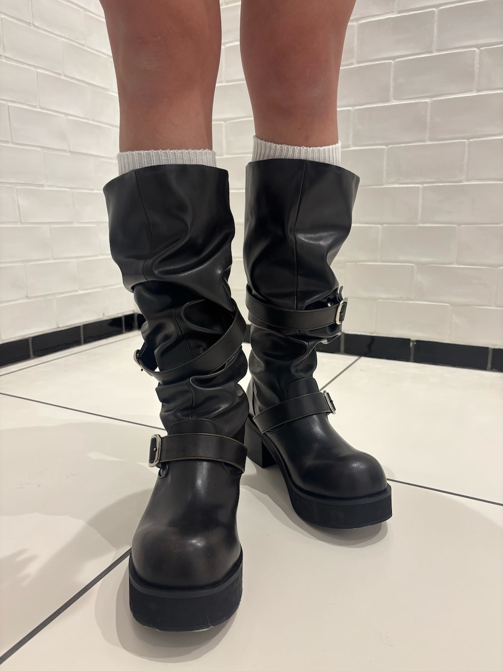 ホワイト系のニット/セーター、ブルー系のスカート、ブラック系のブーツを着用したレディースの冬コーディネートの7枚目の写真