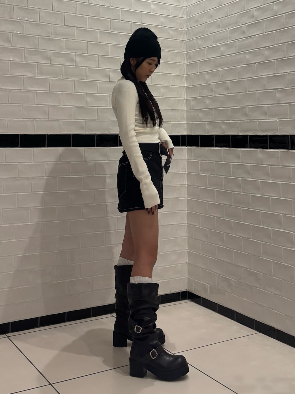 ホワイト系のニット/セーター、ブルー系のスカート、ブラック系のブーツを着用したレディースの冬コーディネートの2枚目の写真