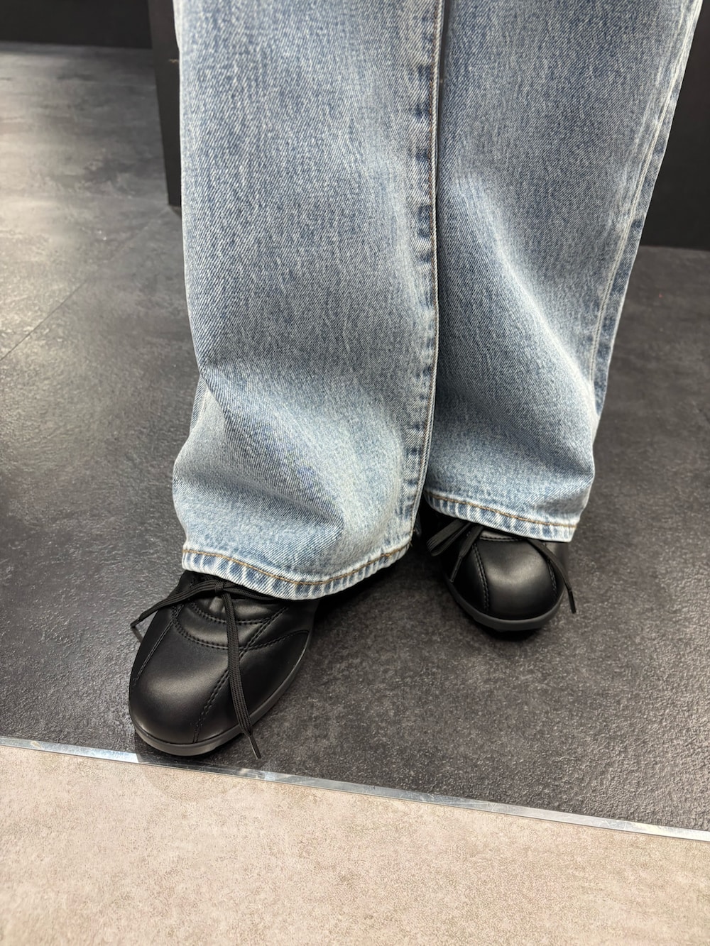 ブラック系のTシャツ/カットソー、ブルー系のデニムパンツ、ホワイト系のショルダーバッグを着用したレディースの春コーディネートの6枚目の写真