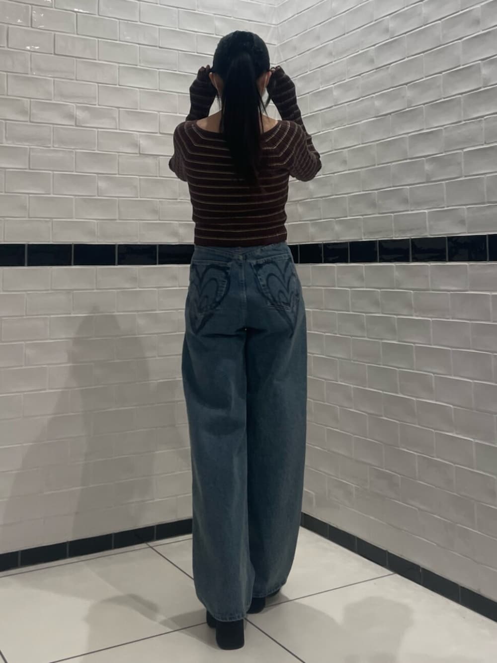 ブラウン系のニット/セーター、ブルー系のデニムパンツ、ブラック系のブーツを着用したレディースの冬コーディネートの3枚目の写真