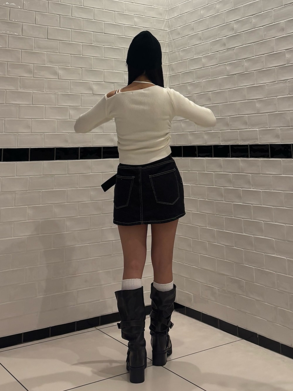 ホワイト系のニット/セーター、ブルー系のスカート、ブラック系のブーツを着用したレディースの冬コーディネートの3枚目の写真