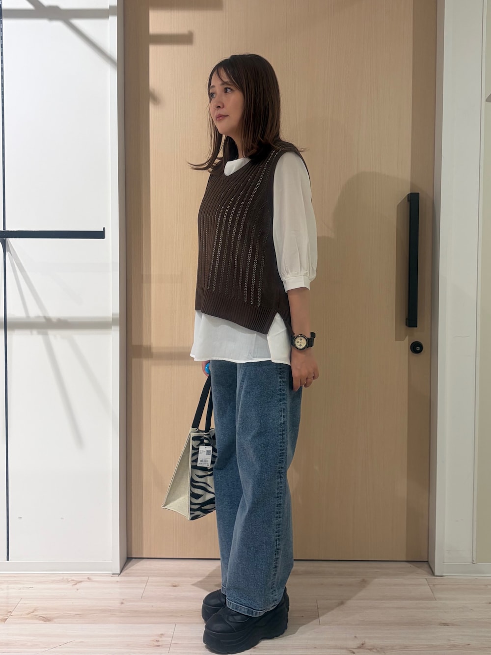 ブルー系のデニムパンツ、ブラック系のトートバッグを着用したレディースの秋コーディネートの2枚目の写真