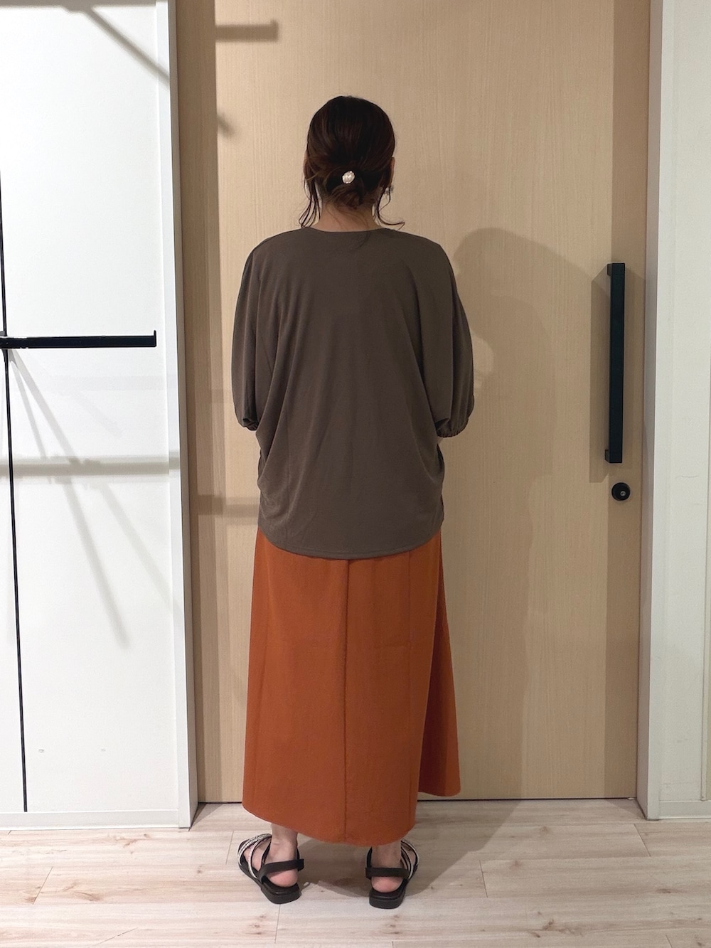 オレンジ系のワンピース、ブラウン系のカーディガン/ボレロ、イエロー系のトートバッグを着用したレディースの夏コーディネートの3枚目の写真