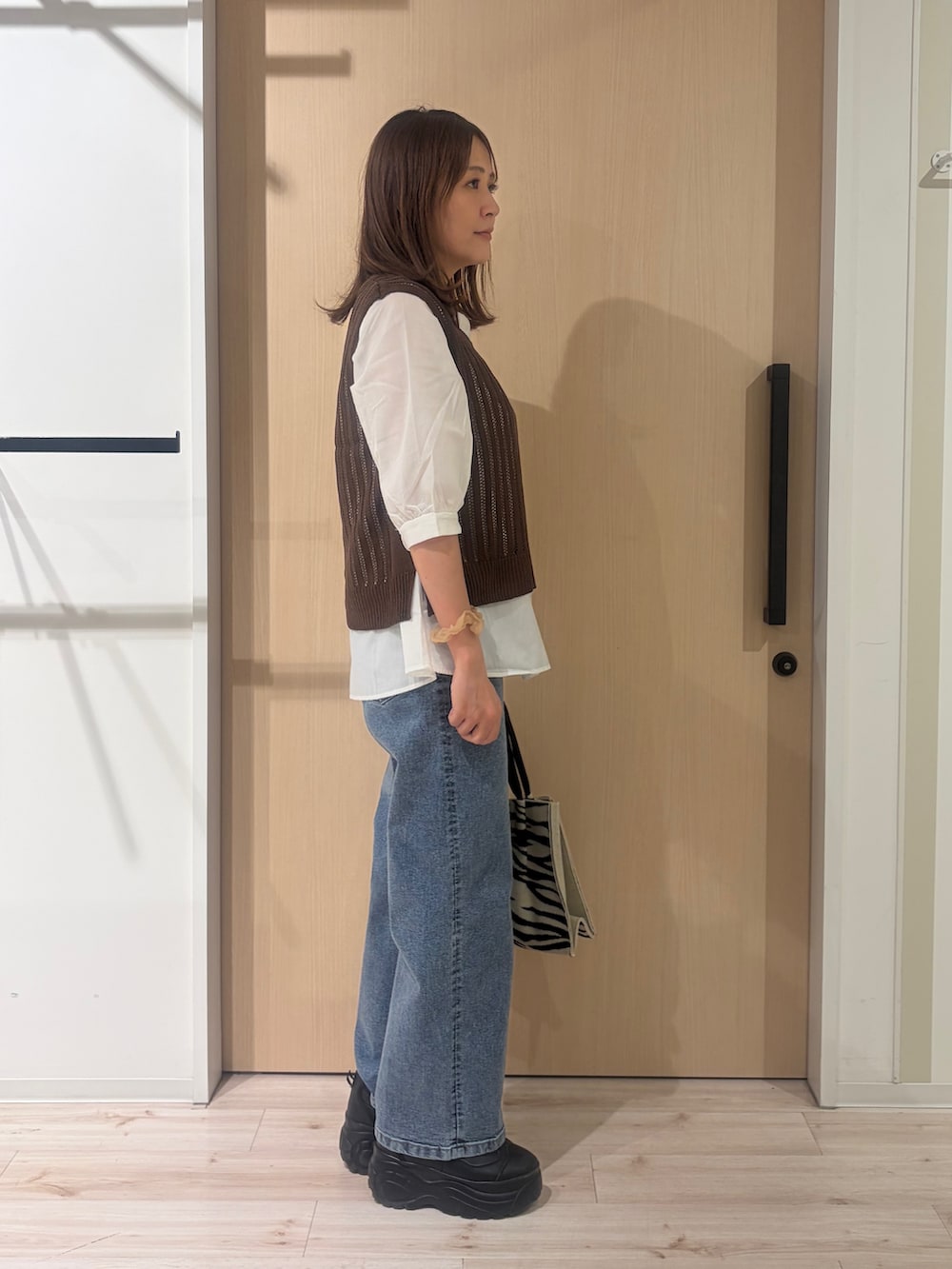 ブルー系のデニムパンツ、ブラック系のトートバッグを着用したレディースの秋コーディネートの3枚目の写真
