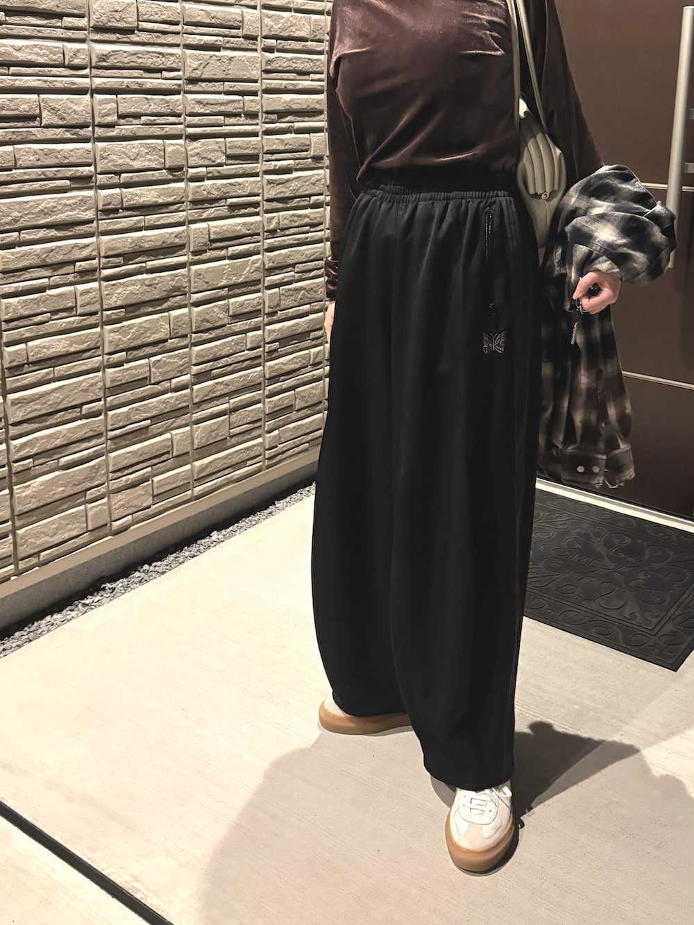 ブラック系のその他パンツ、ホワイト系のスニーカー、ブラウン系のTシャツ/カットソーを着用したレディースの秋コーディネートの2枚目の写真