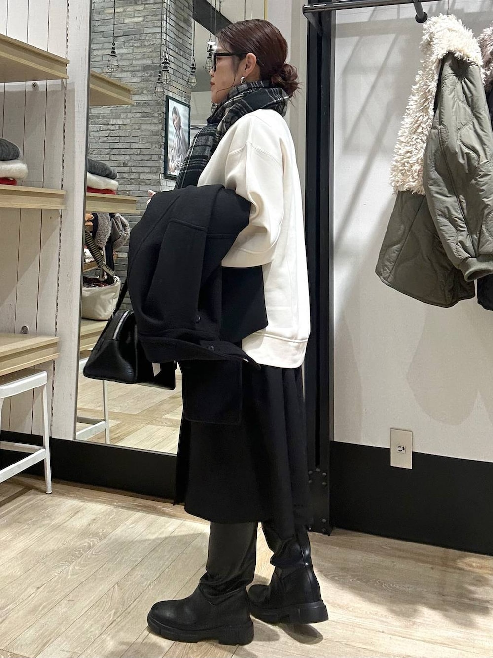 ブラック系のその他アウター、ブラック系のボストンバッグ、ブラック系のブーツを着用したレディースの冬コーディネートの3枚目の写真