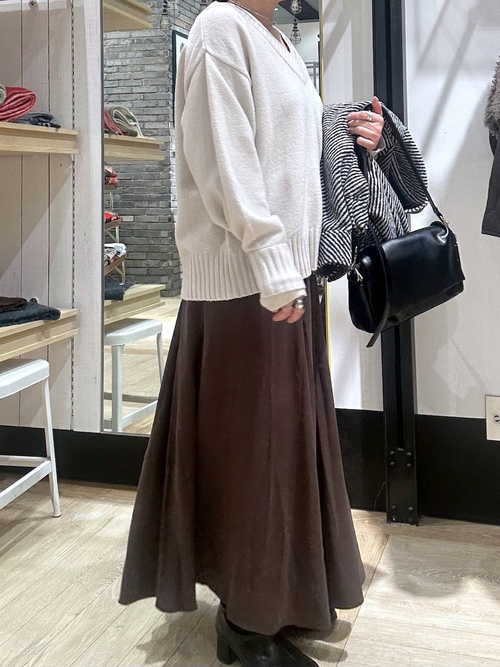 ブラック系のショルダーバッグ、ホワイト系のニット/セーター、ブラック系のブルゾンを着用したレディースの冬コーディネートの3枚目の写真