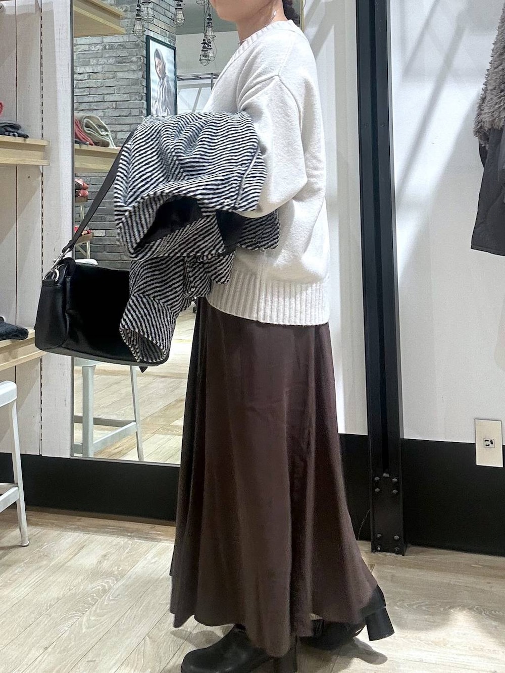 ブラック系のショルダーバッグ、ホワイト系のニット/セーター、ブラック系のブルゾンを着用したレディースの冬コーディネートの6枚目の写真