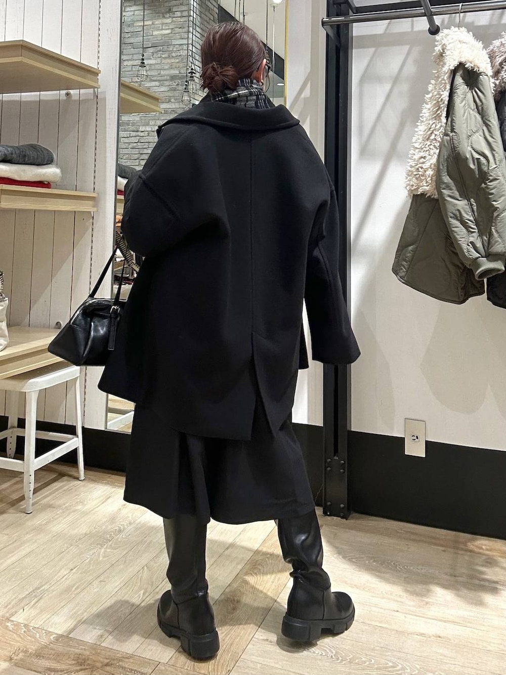 ブラック系のその他アウター、ブラック系のボストンバッグ、ブラック系のブーツを着用したレディースの冬コーディネートの5枚目の写真