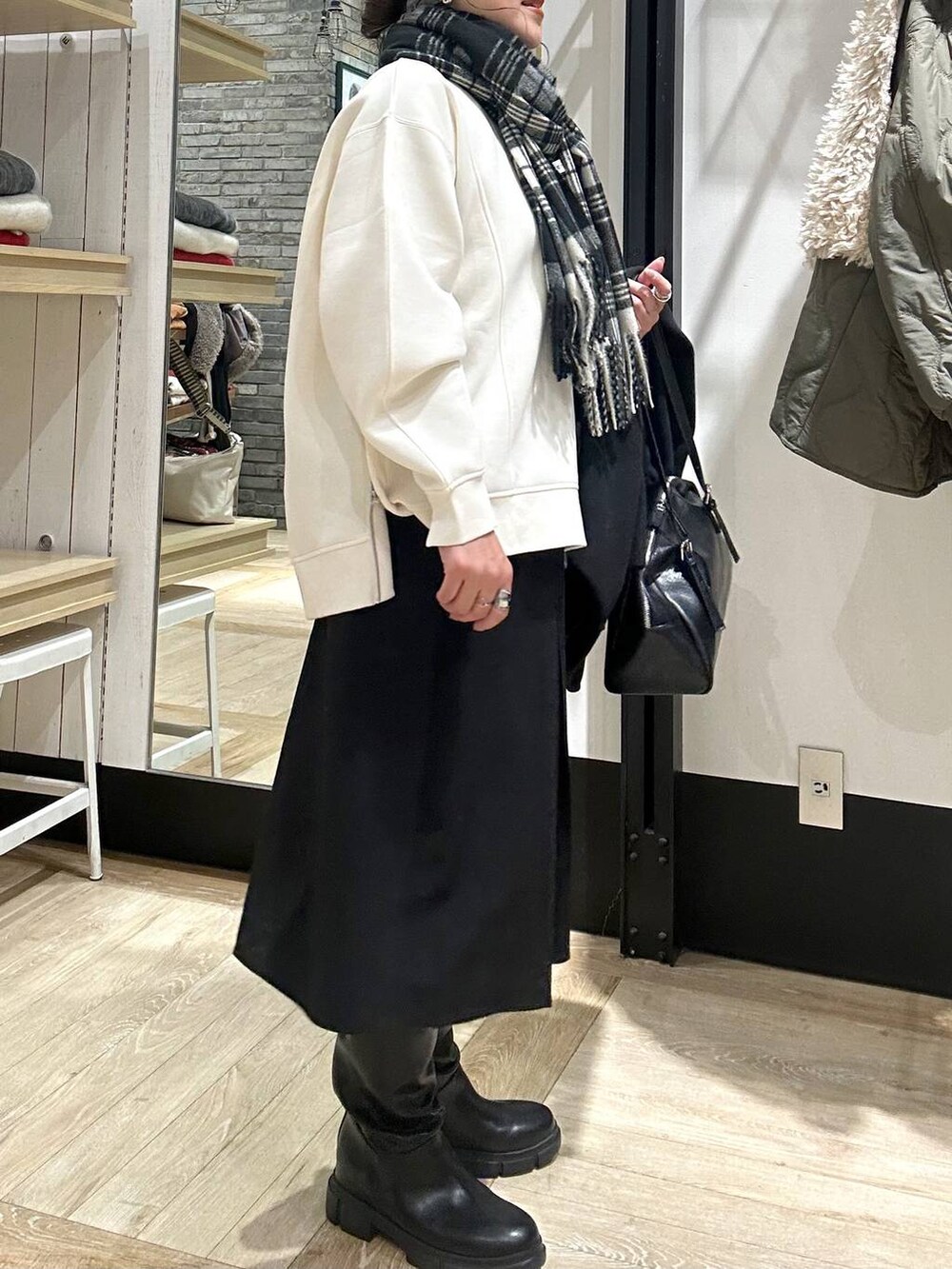 ブラック系のその他アウター、ブラック系のボストンバッグ、ブラック系のブーツを着用したレディースの冬コーディネートの6枚目の写真