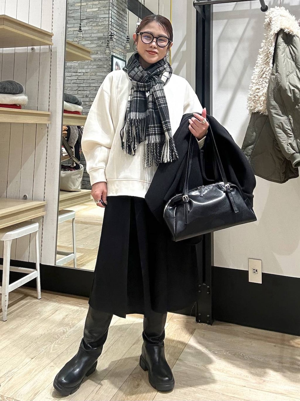 ブラック系のその他アウター、ブラック系のボストンバッグ、ブラック系のブーツを着用したレディースの冬コーディネートの2枚目の写真