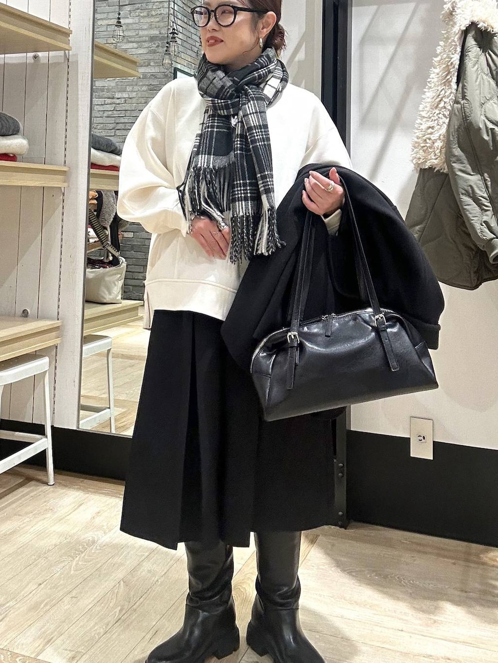 ブラック系のその他アウター、ブラック系のボストンバッグ、ブラック系のブーツを着用したレディースの冬コーディネートの7枚目の写真