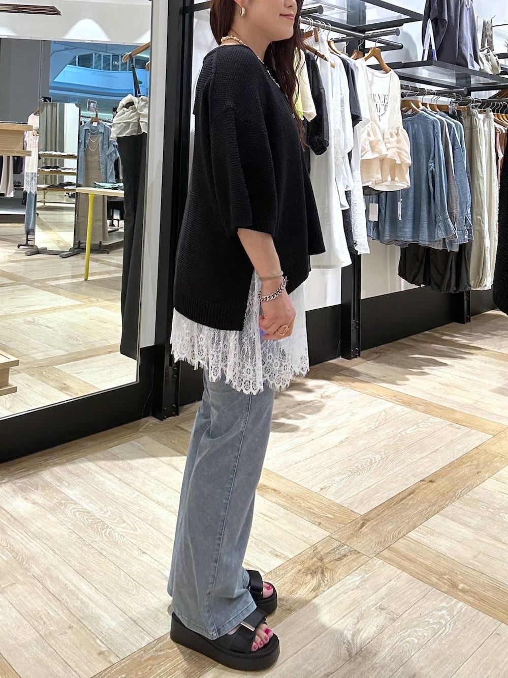 ホワイト系のキャミソール、ブラック系のサンダル、ブルー系のデニムパンツを着用したレディースの夏コーディネートの4枚目の写真