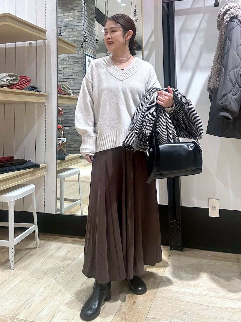 ブラック系のショルダーバッグ、ホワイト系のニット/セーター、ブラック系のブルゾンを着用したレディースの冬コーディネートの2枚目の写真