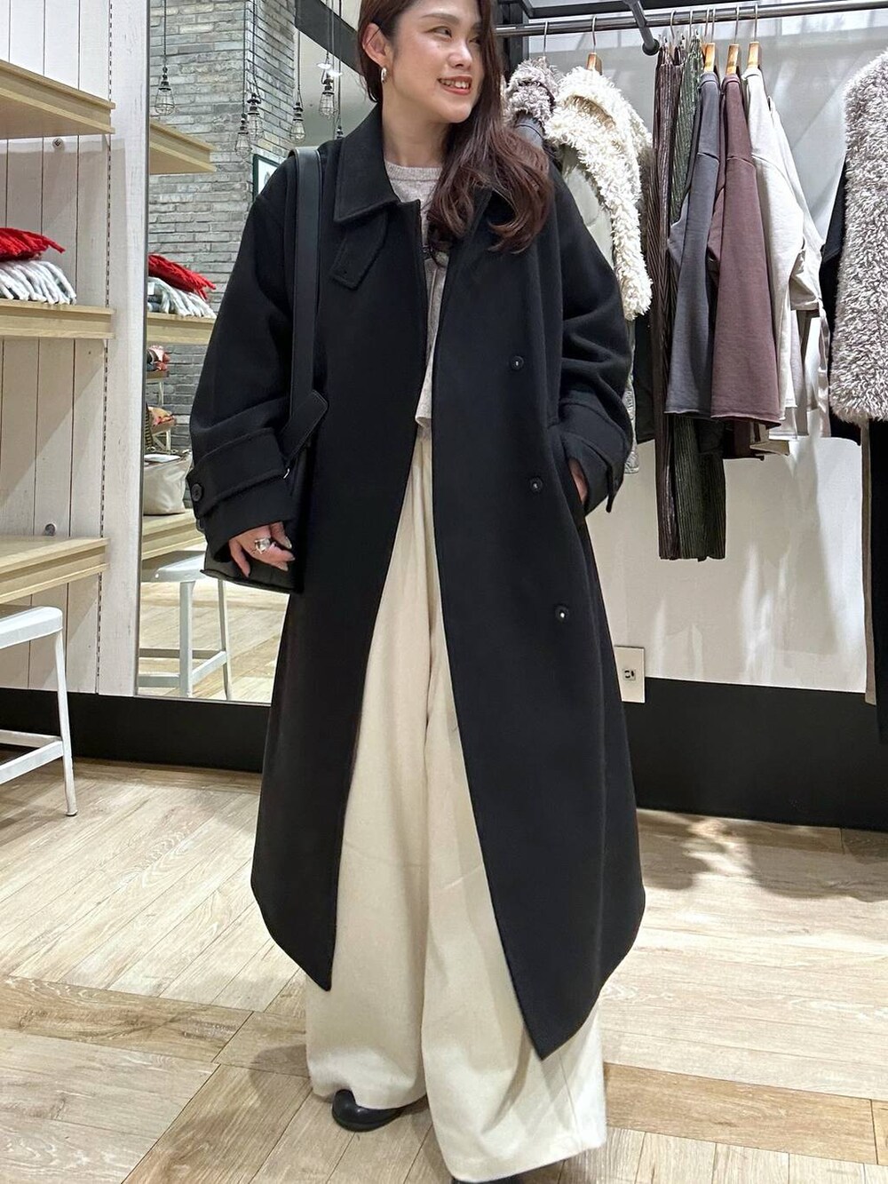 ブラック系のステンカラーコート、ブラック系のショルダーバッグ、ブラック系のブーツを着用したレディースの冬コーディネートの6枚目の写真