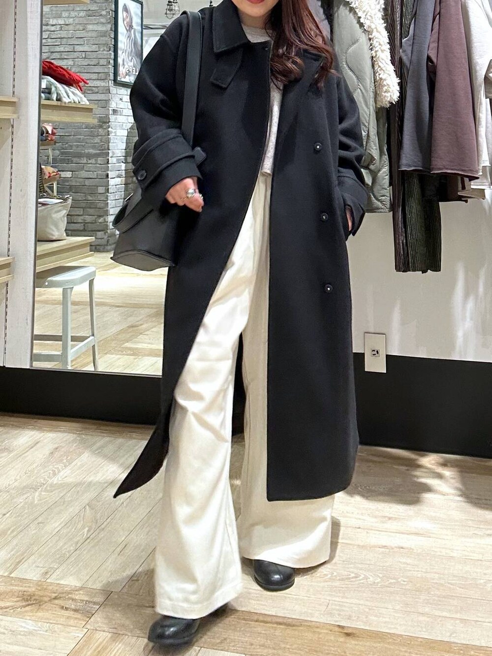 ブラック系のステンカラーコート、ブラック系のショルダーバッグ、ブラック系のブーツを着用したレディースの冬コーディネートの5枚目の写真