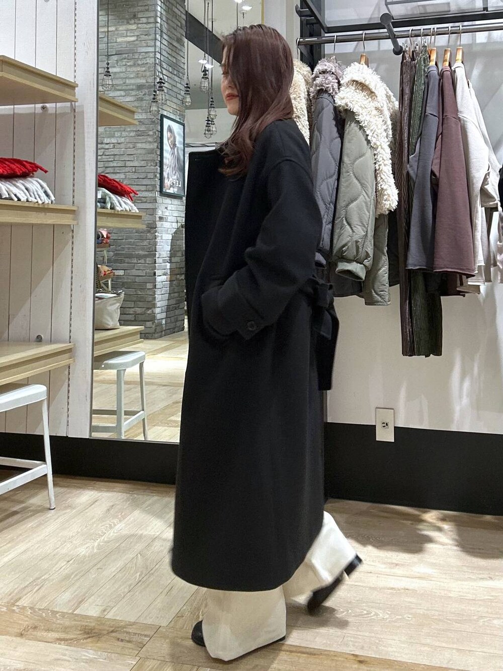 ブラック系のステンカラーコート、ブラック系のショルダーバッグ、ブラック系のブーツを着用したレディースの冬コーディネートの2枚目の写真