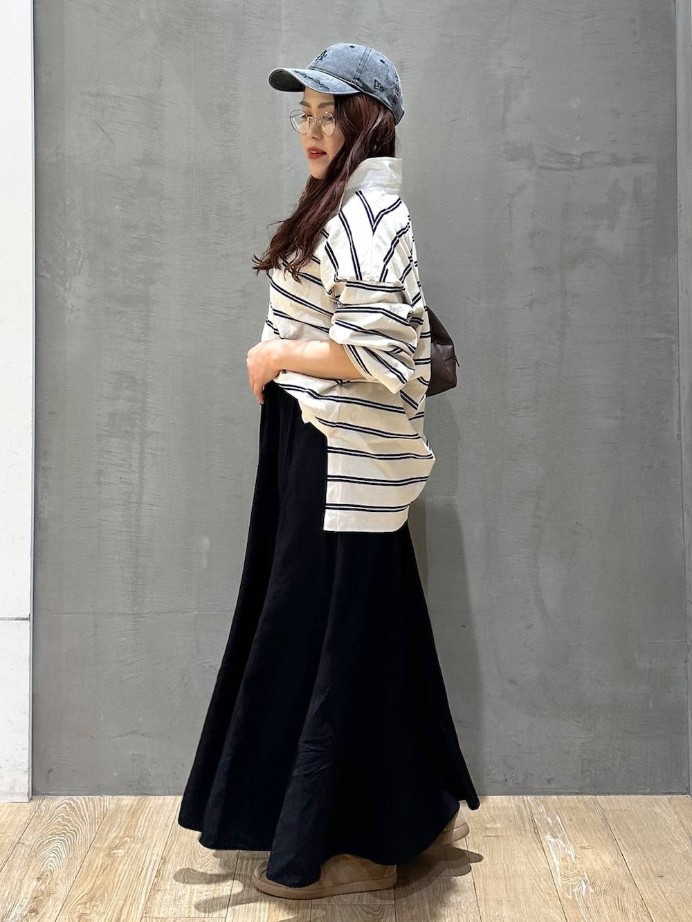 ブラウン系のボストンバッグ、ブラック系のスカート、ブラック系のキャップを着用したレディースの冬コーディネートの2枚目の写真