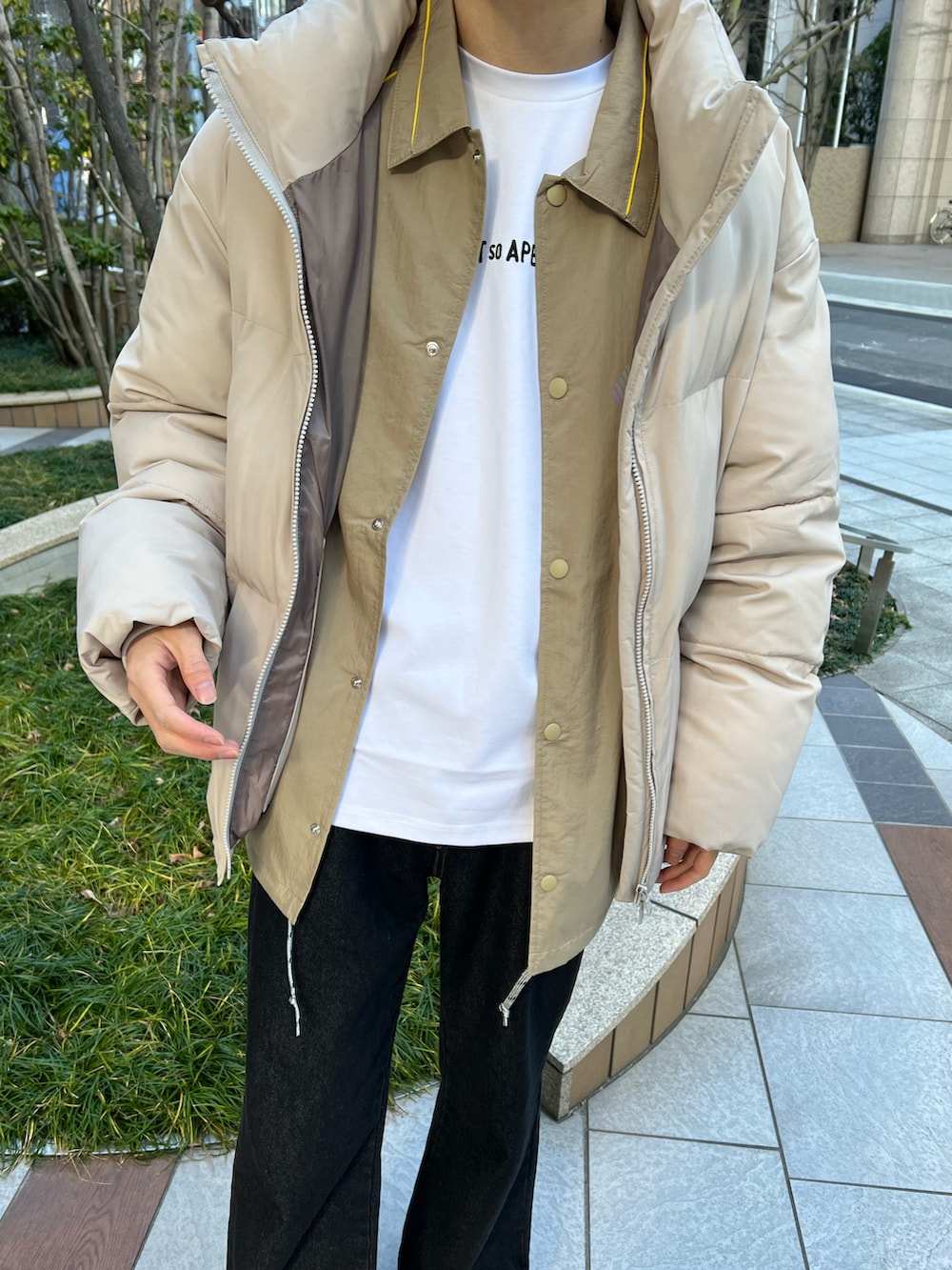 ブラック系のデニムパンツ、ベージュ系のナイロンジャケット、ホワイト系のTシャツ/カットソーを着用したメンズの冬コーディネートの2枚目の写真