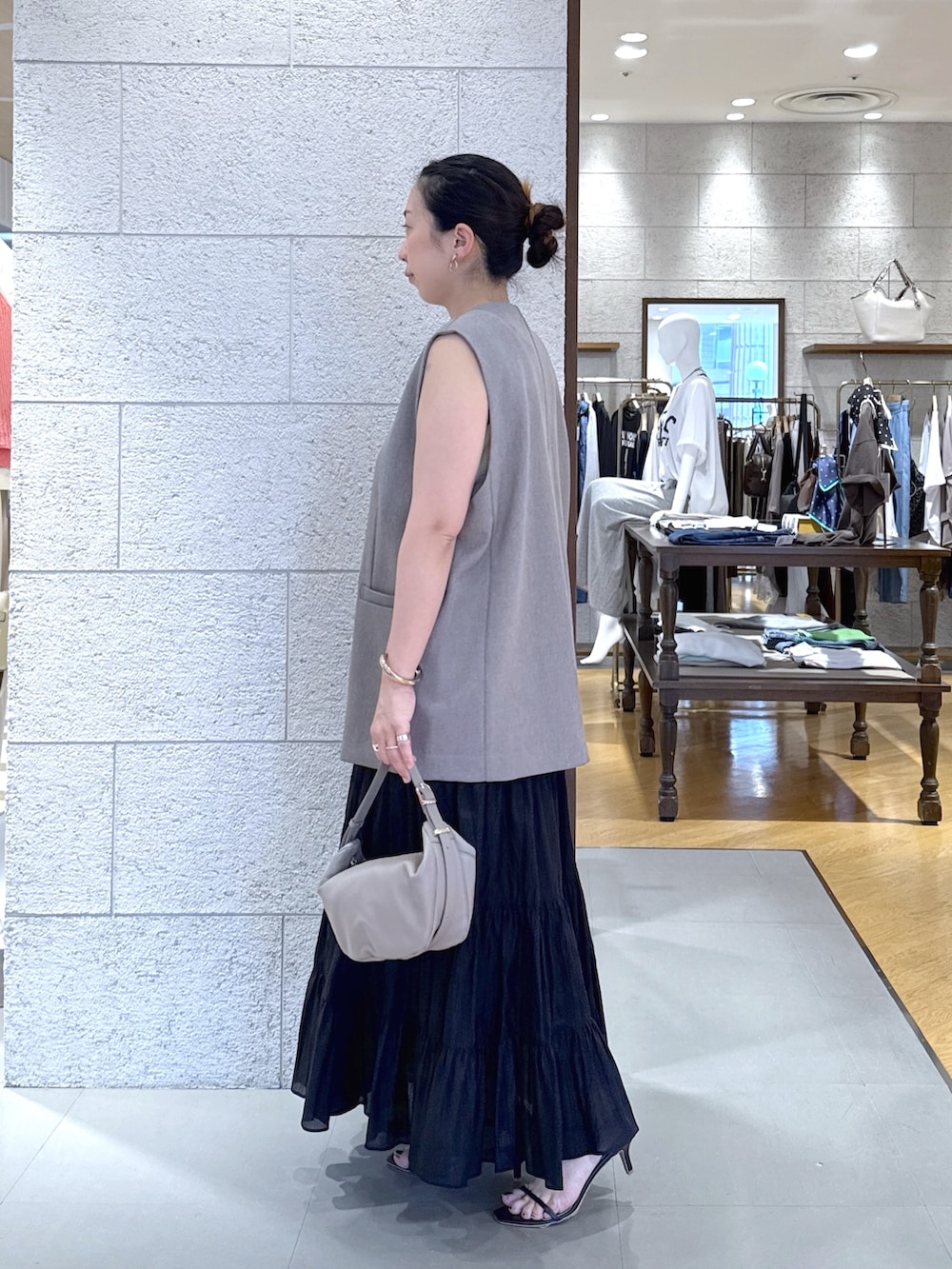 ブラウン系のベスト、ブラック系のスカート、ベージュ系のショルダーバッグを着用したレディースの夏コーディネートの2枚目の写真