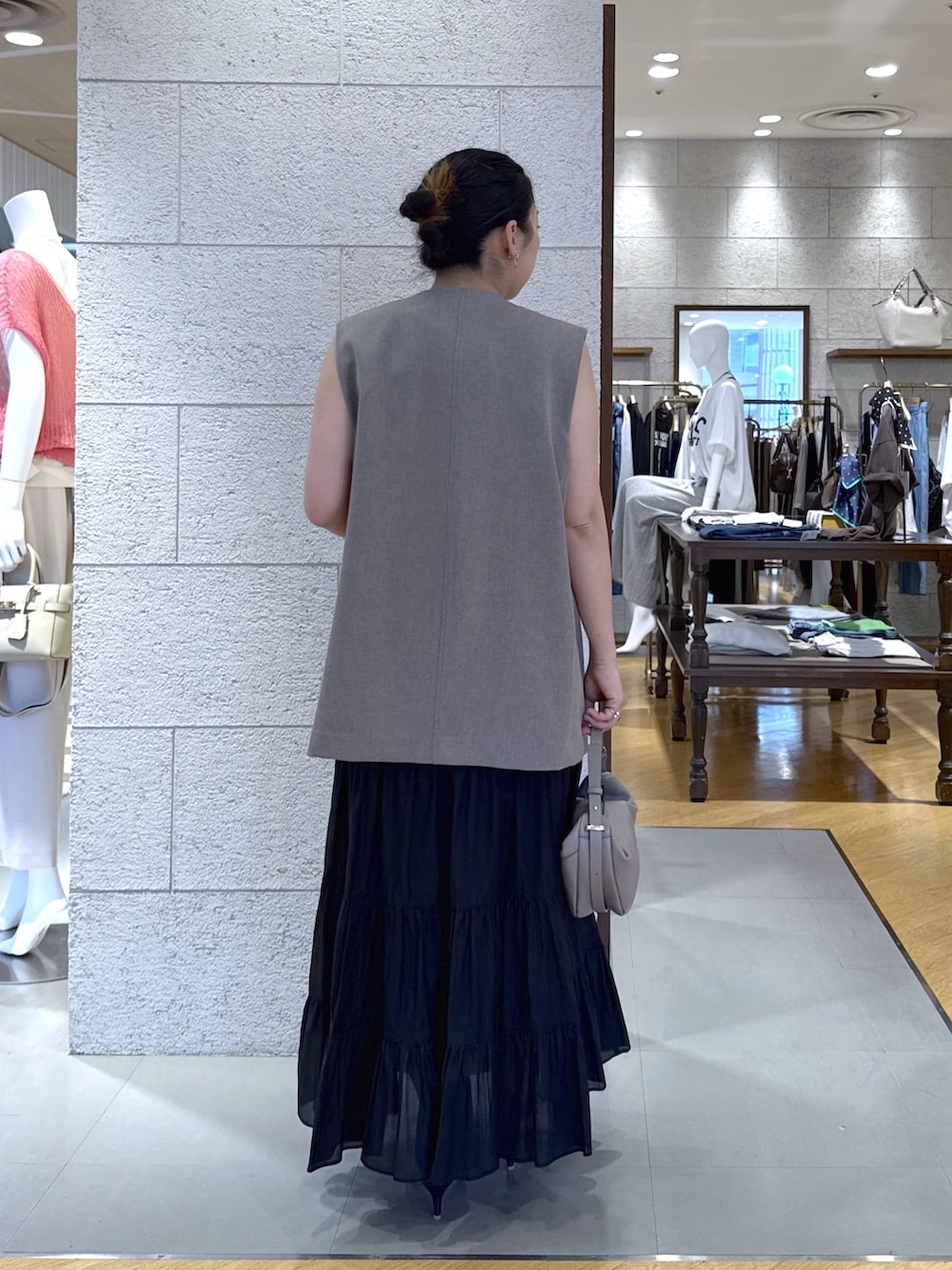 ブラウン系のベスト、ブラック系のスカート、ベージュ系のショルダーバッグを着用したレディースの夏コーディネートの3枚目の写真