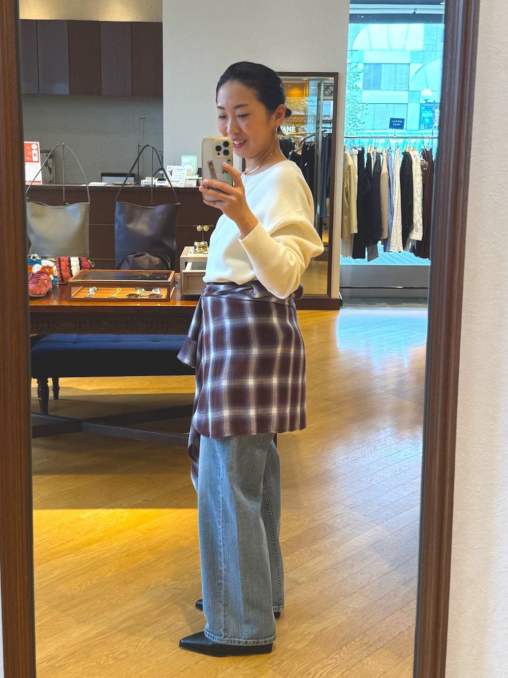 ホワイト系のニット/セーター、ブラウン系のシャツ/ブラウス、ブルー系のデニムパンツを着用したレディースの秋コーディネートの2枚目の写真