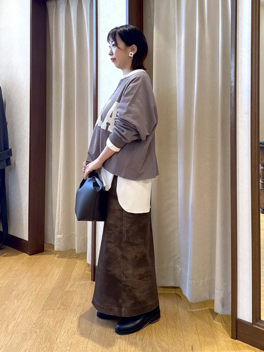 ブラウン系のスウェット、ホワイト系のTシャツ/カットソー、ブラック系のハンドバッグを着用したレディースの秋コーディネートの3枚目の写真