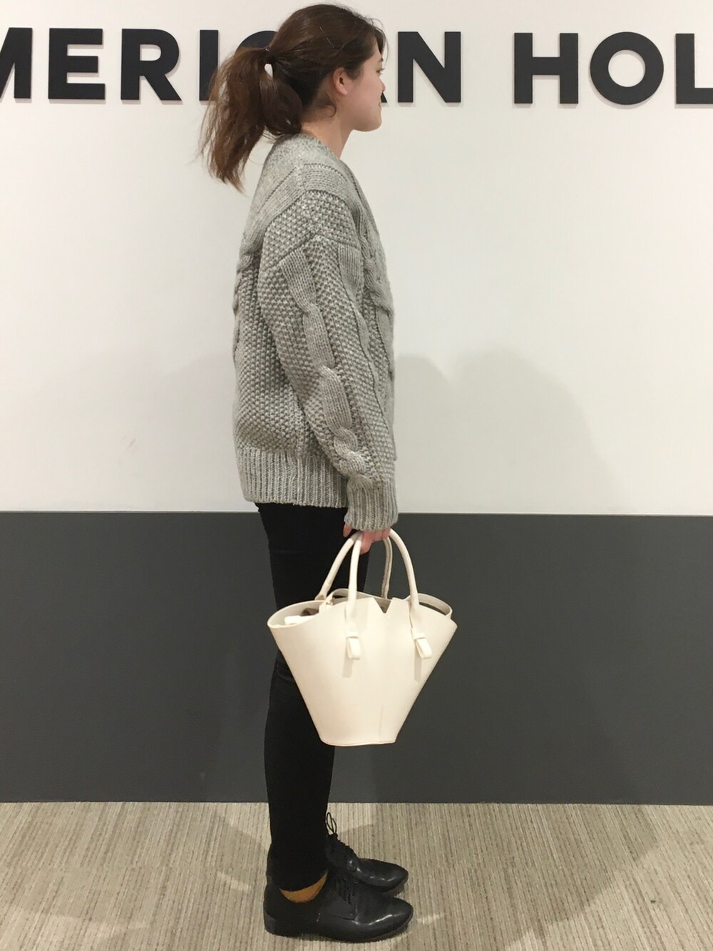 グレー系のニット/セーター、ブラック系のデニムパンツ、ブラック系のドレスシューズを着用したレディースの秋コーディネートの2枚目の写真