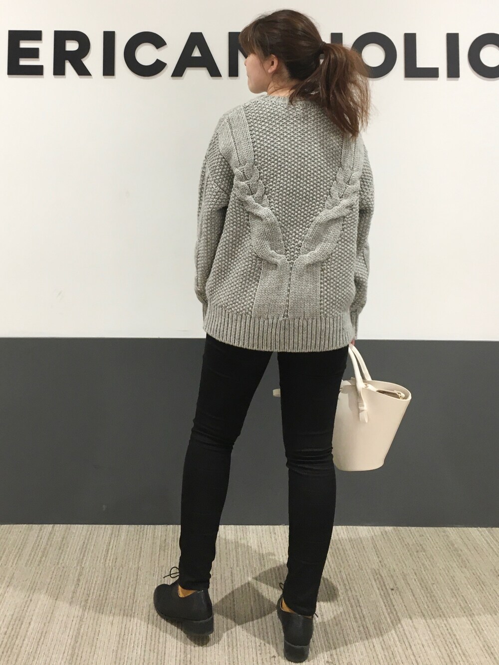 グレー系のニット/セーター、ブラック系のデニムパンツ、ブラック系のドレスシューズを着用したレディースの秋コーディネートの3枚目の写真