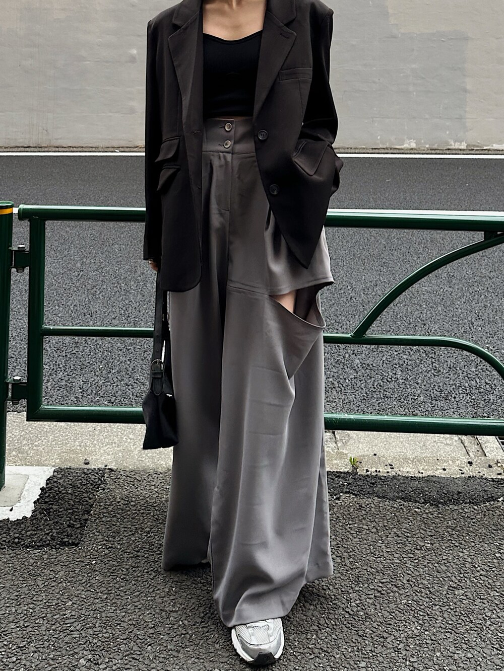 ブラック系のテーラードジャケット、ブルー系のハンドバッグ、グレー系のパンツを着用したレディースの春コーディネートの5枚目の写真