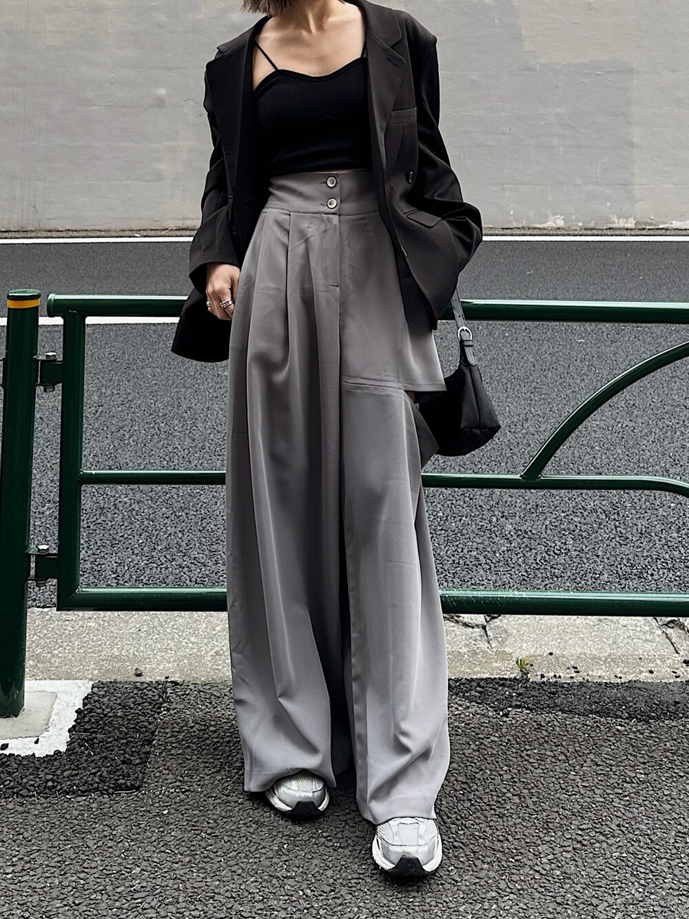 ブラック系のテーラードジャケット、ブルー系のハンドバッグ、グレー系のパンツを着用したレディースの春コーディネートの4枚目の写真