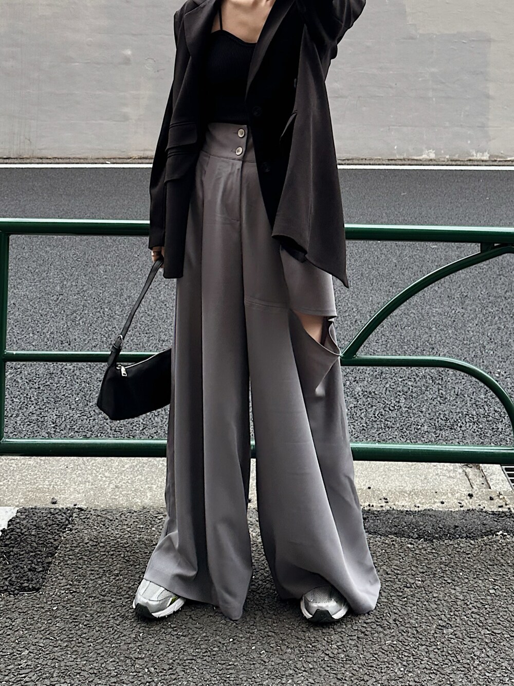 ブラック系のテーラードジャケット、ブルー系のハンドバッグ、グレー系のパンツを着用したレディースの春コーディネートの3枚目の写真