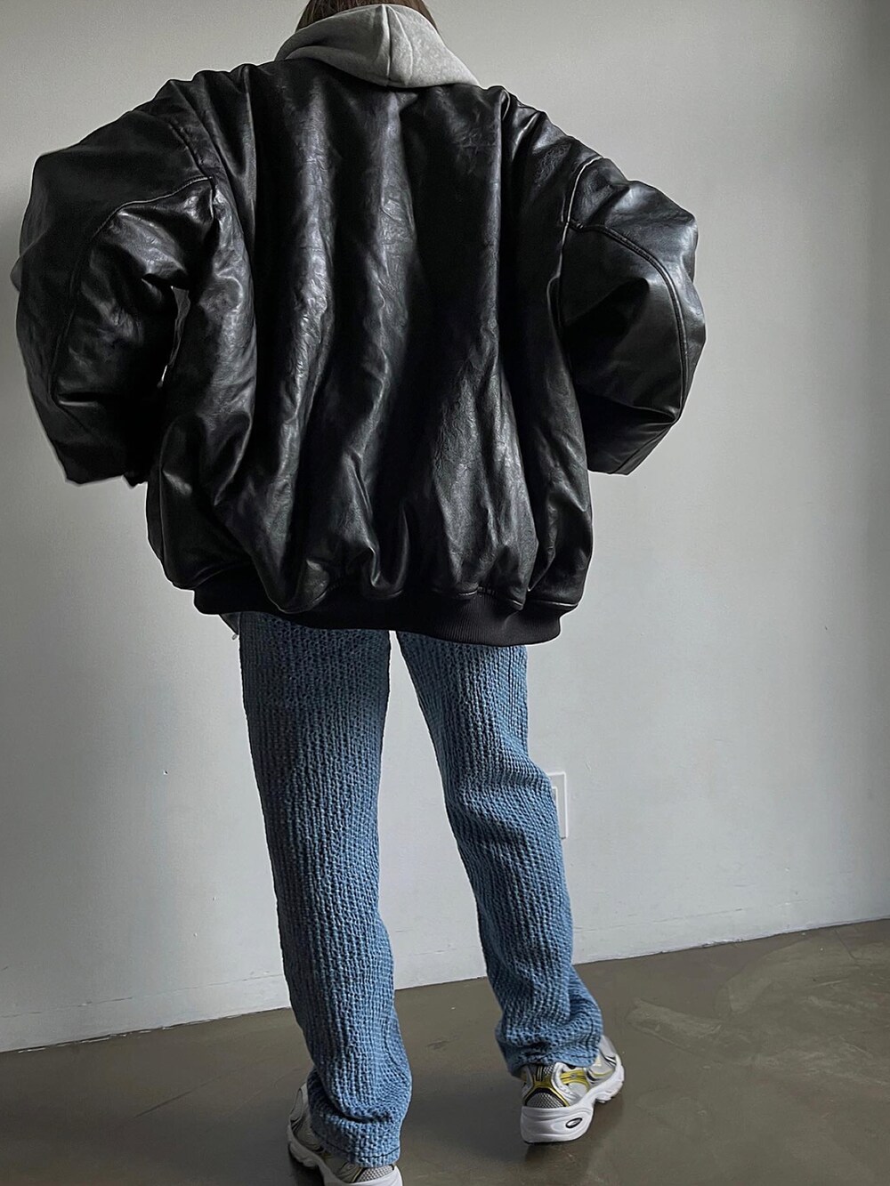 ブラック系のMA-1、ブルー系のパンツ、ホワイト系のスニーカーを着用したレディースの冬コーディネートの2枚目の写真