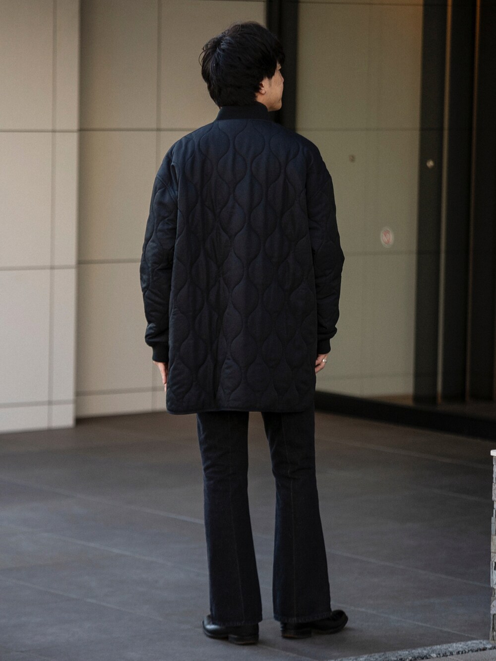 ブラック系のダウンジャケット/コート、グレー系のニット/セーター、ブルー系のデニムパンツを着用したメンズの冬コーディネートの4枚目の写真