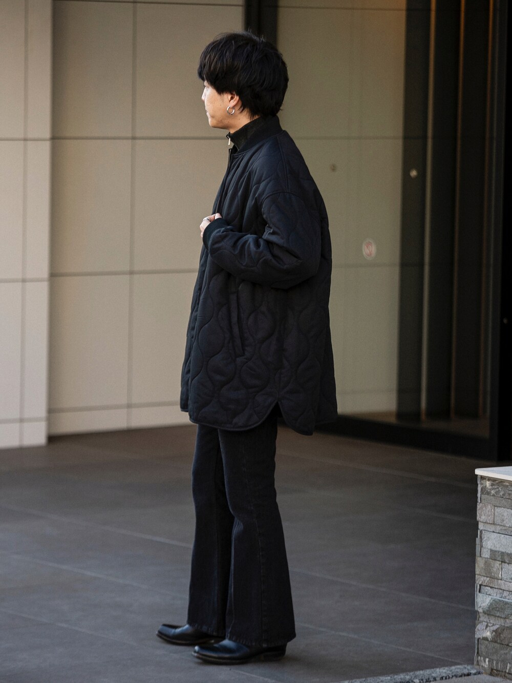 ブラック系のダウンジャケット/コート、グレー系のニット/セーター、ブルー系のデニムパンツを着用したメンズの冬コーディネートの3枚目の写真