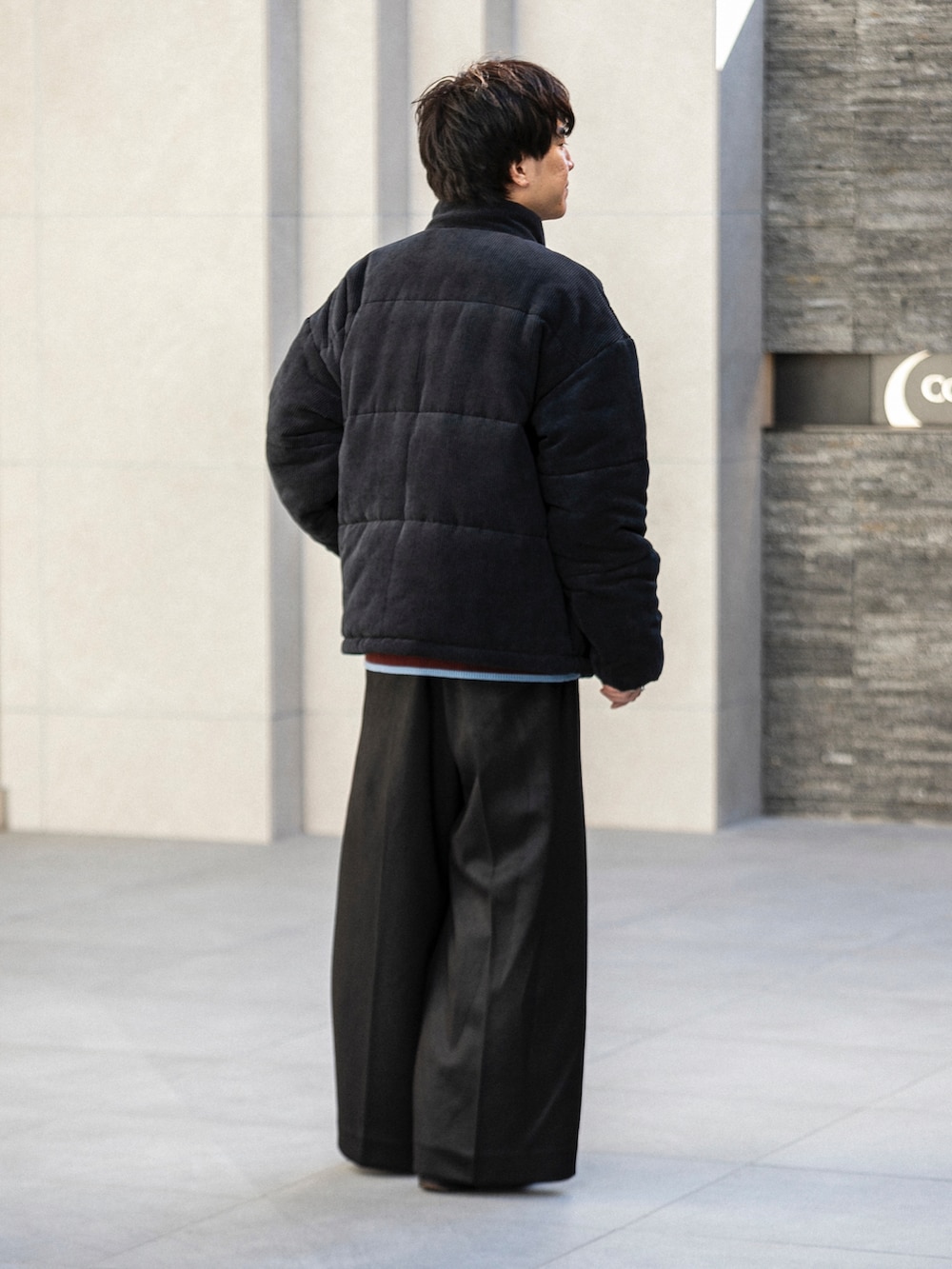 ブラック系のダウンジャケット/コート、ホワイト系のニット/セーター、ブラック系のその他パンツを着用したメンズの冬コーディネートの3枚目の写真