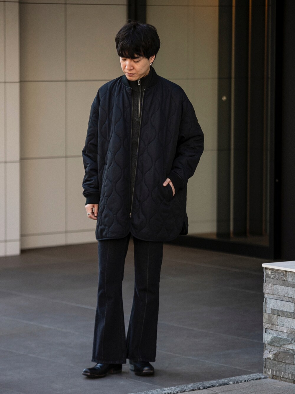 ブラック系のダウンジャケット/コート、グレー系のニット/セーター、ブルー系のデニムパンツを着用したメンズの冬コーディネートの2枚目の写真