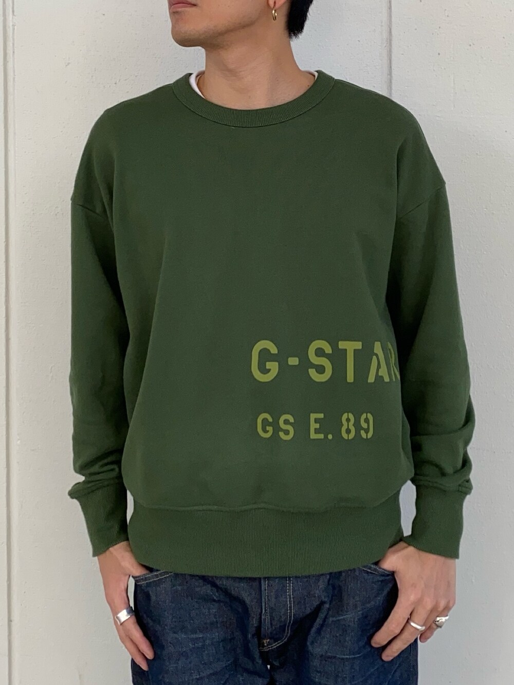 ブラック系のデニムジャケット、グリーン系のスウェット、ブルー系のデニムパンツを着用したメンズの秋コーディネートの2枚目の写真